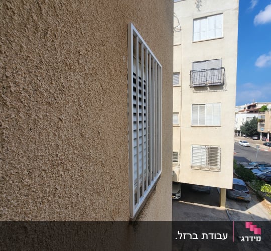 סורג מתכת לבן על חלון קיר חיצוני